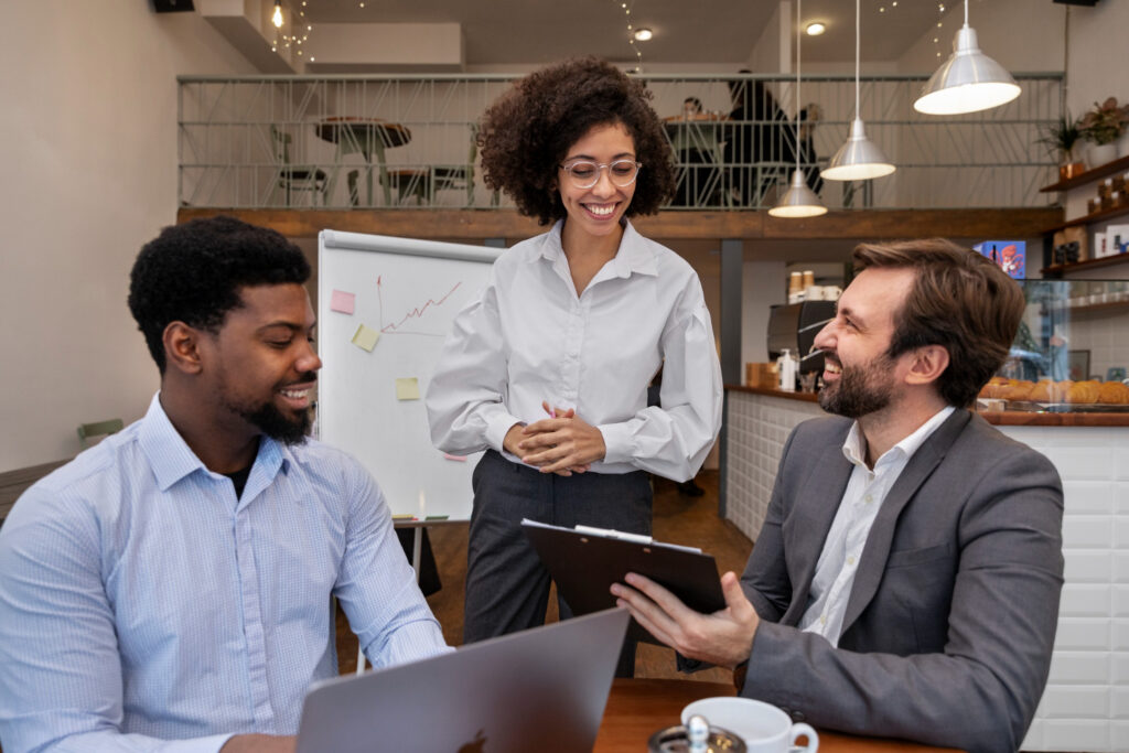 Três pessoas conversam em um estabelecimento comercial, ambiente relacionado à gestão de equipes e jornadas de trabalho.