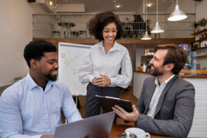 Três pessoas conversam em um estabelecimento comercial, ambiente relacionado à gestão de equipes e jornadas de trabalho.